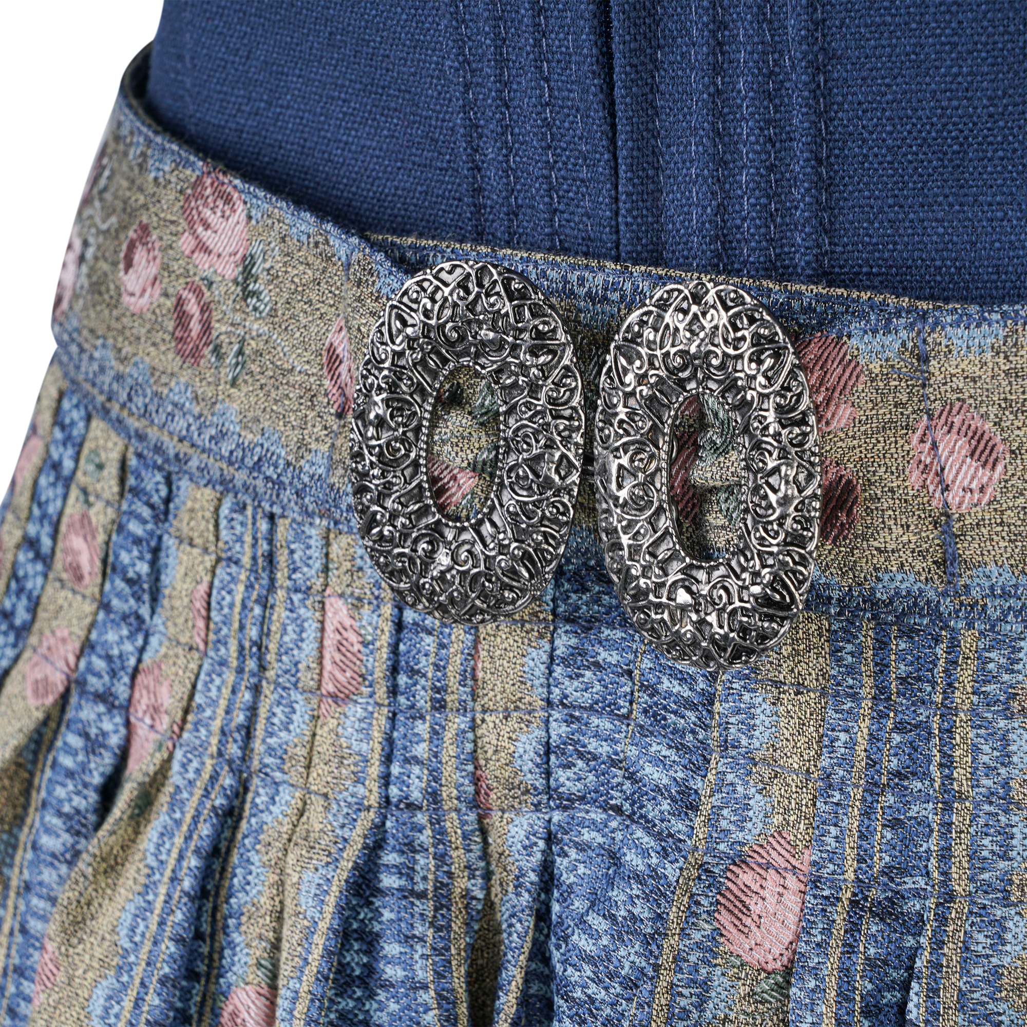 Nahaufnahme eines Dirndl-Gürtels aus blau-gemustertem Stoff mit Rosendekor; im Zentrum befindet sich eine silberne, ovale Metallschließe mit filigranem Muster.